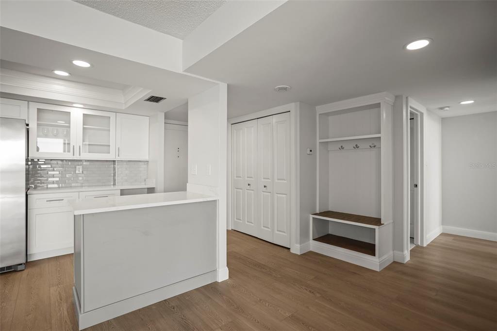 A kitchen with white cabinets and a breakfast bar next to a built-in mudroom bench — 400 ISLAND WAY UNIT 602, CLEARWATER BEACH, FL