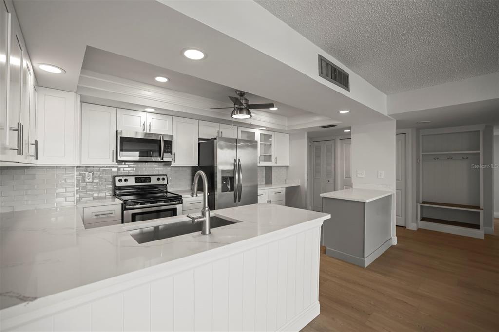 A modern kitchen features white cabinetry, stainless steel appliances, and a marble-topped island — 400 ISLAND WAY UNIT 602, CLEARWATER BEACH, FL