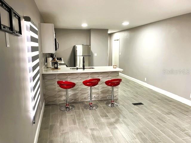 A kitchen features a breakfast bar with three red stools and gray tile flooring — 15731 SE 72ND PLACE, MORRISTON, FL