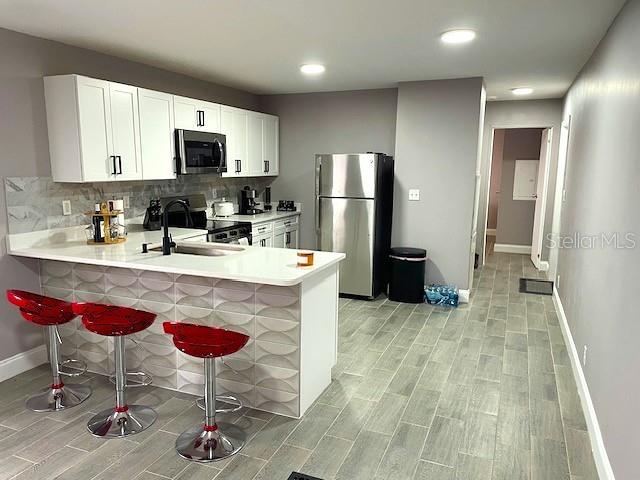 A modern kitchen features white cabinets, stainless steel appliances, and a textured breakfast bar — 15731 SE 72ND PLACE, MORRISTON, FL