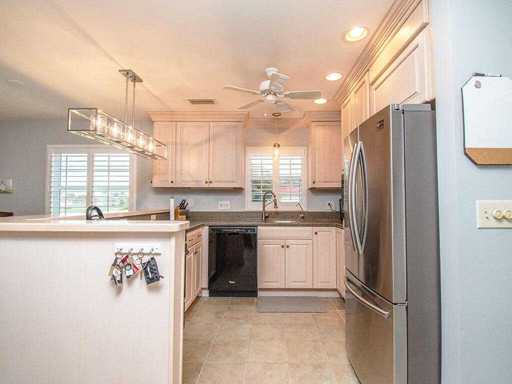 A kitchen features light wood cabinets, stainless steel appliances, and a hanging rectangular light fixture — VERO BEACH, FL
