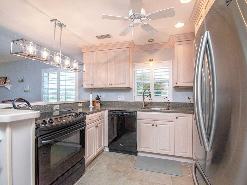 A kitchen features light wood cabinets, dark countertops, black appliances, and a stainless steel refrigerator — VERO BEACH, FL