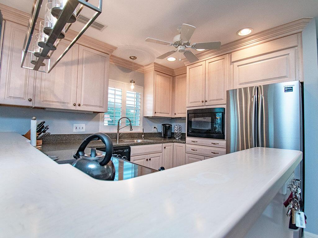 A kitchen features light wood cabinets, stainless steel appliances, and a white countertop breakfast bar — VERO BEACH, FL