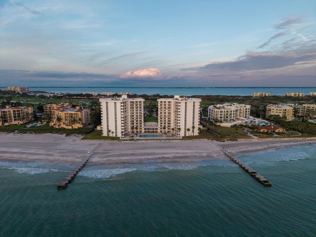 An aerial view of a beachfront condominium complex with two towers and two wooden piers — 2295 GULF OF MEXICO DRIVE UNIT 54S, LONGBOAT KEY, FL