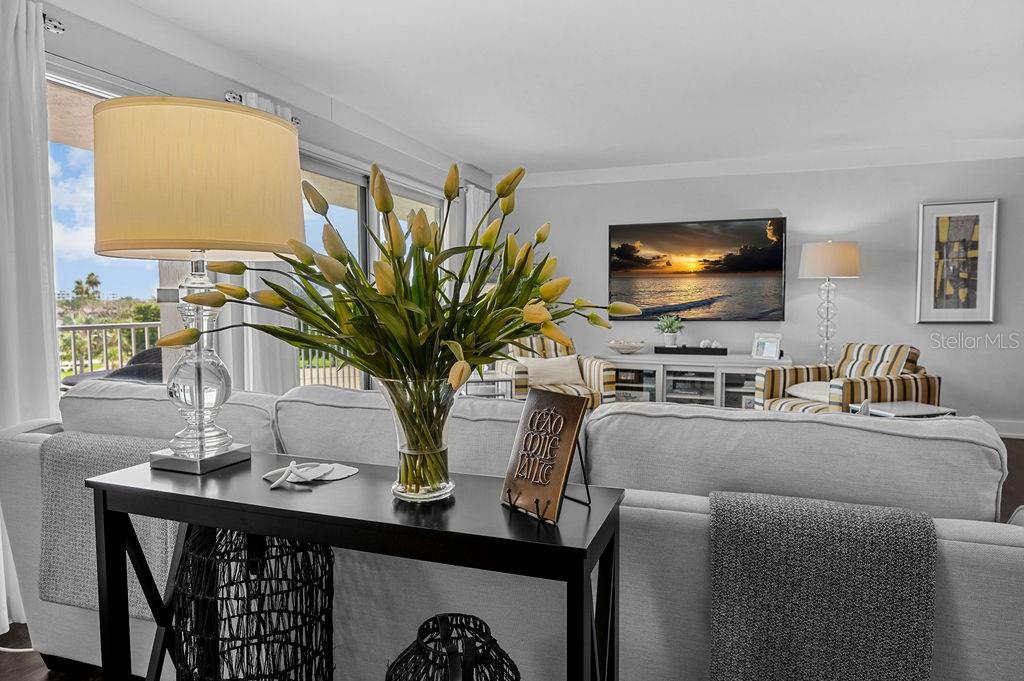 A living room features a sofa, a console table with a floral arrangement, and a television — 2295 GULF OF MEXICO DRIVE UNIT 54S, LONGBOAT KEY, FL