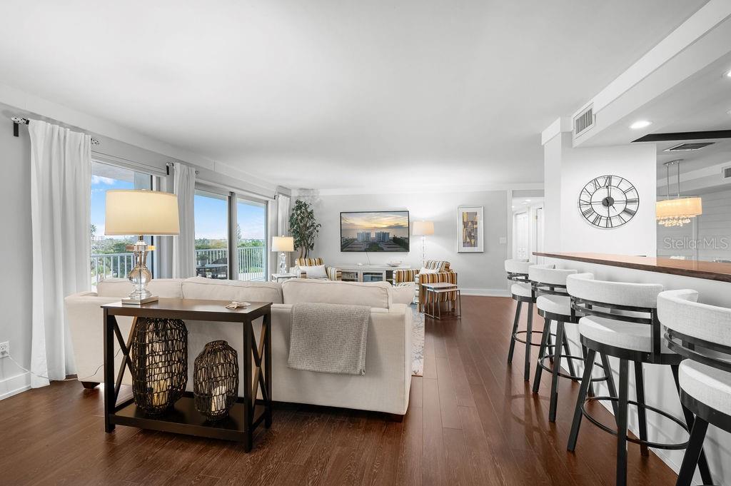 A living room with a sofa, breakfast bar, and sliding glass doors leading to a balcony — 2295 GULF OF MEXICO DRIVE UNIT 54S, LONGBOAT KEY, FL