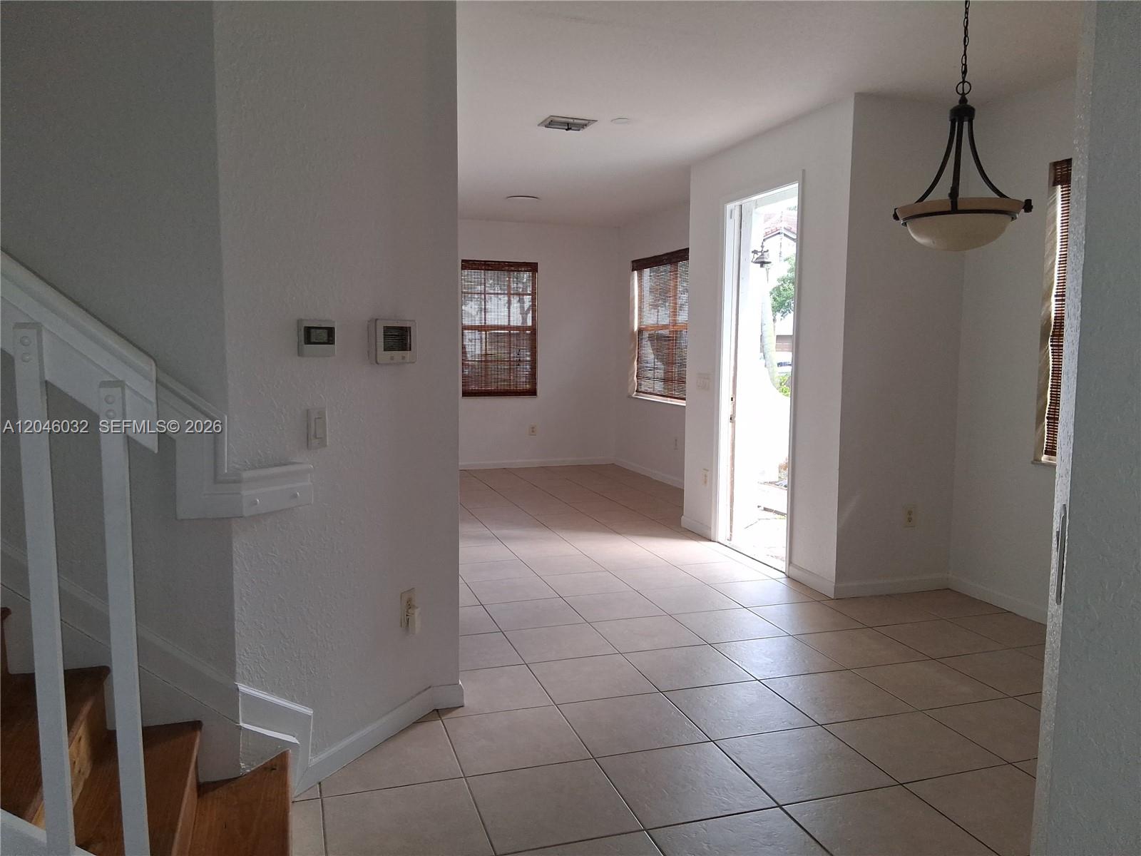 An interior view shows a tiled living area with a staircase and a glass door — 1044 NE 30th Ave, Homestead FL 33033, HOMESTEAD, FL