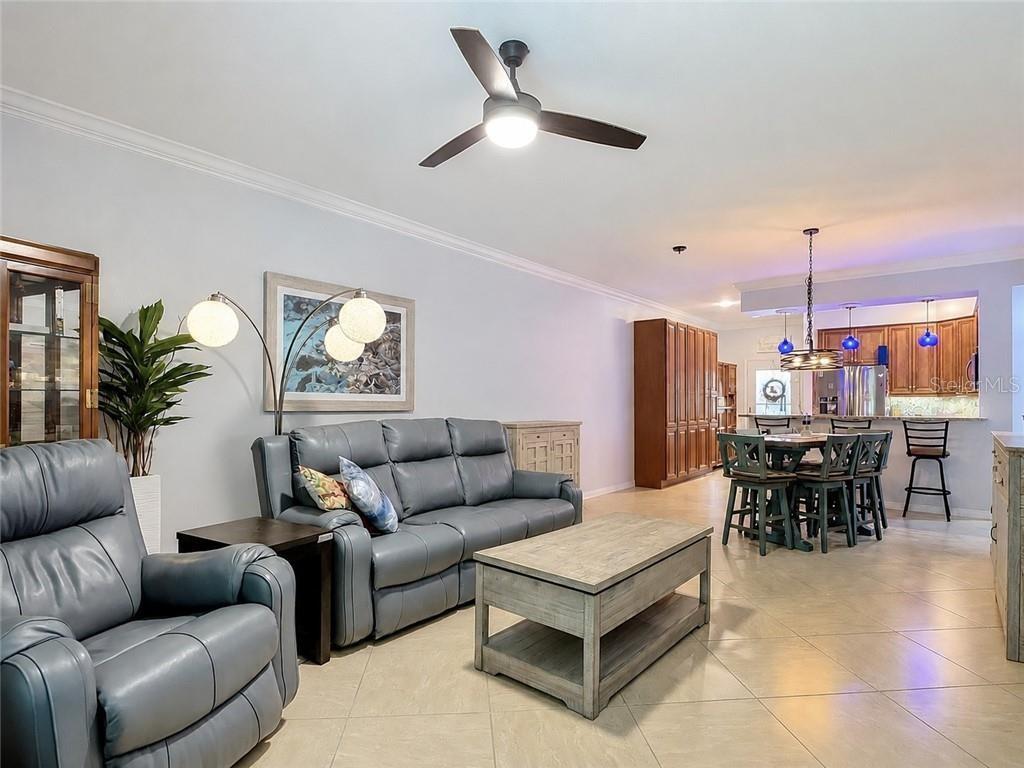 A living room with gray leather furniture, a wooden coffee table, and an open kitchen — 1051 WINDING PINES CIRCLE UNIT 105, CAPE CORAL, FL