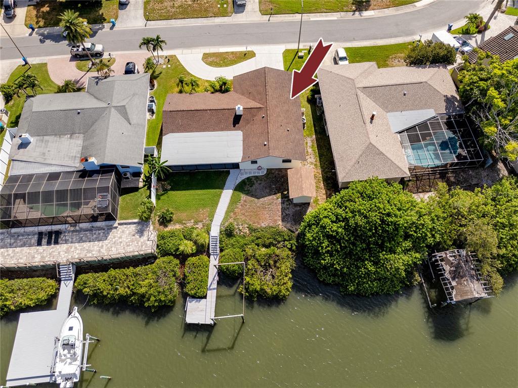 An aerial view shows a waterfront house with a brown roof, dock, and backyard — 8046 BAYHAVEN DRIVE, SEMINOLE, FL