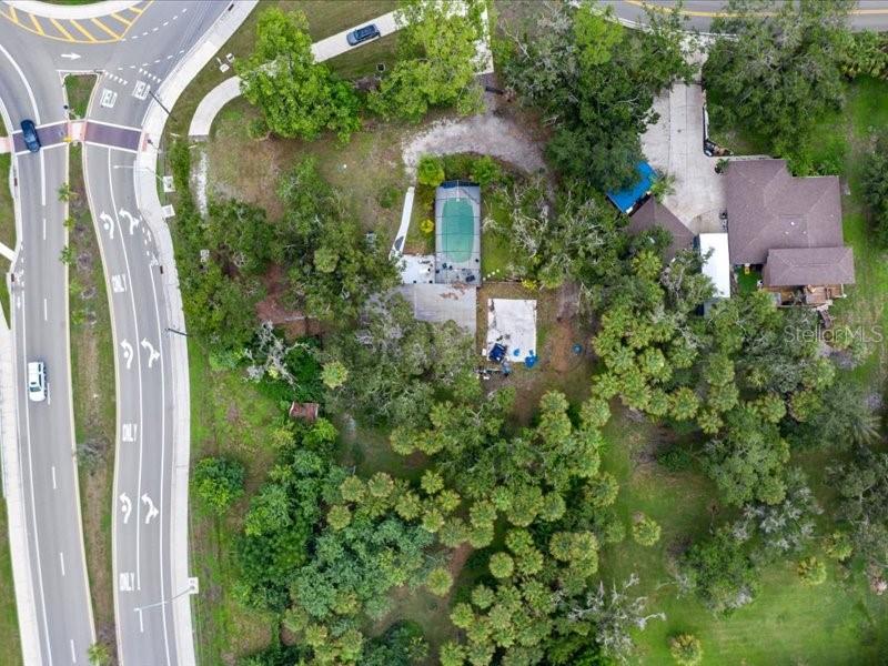 An aerial view shows a house with a screened pool and driveway near a road — 2190 LAKEWOOD RANCH BOULEVARD, SARASOTA, FL