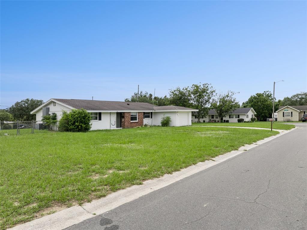 A single-story house with a white exterior, brick accents, and a large front lawn — 702 WILDABON AVENUE, LAKE WALES, FL