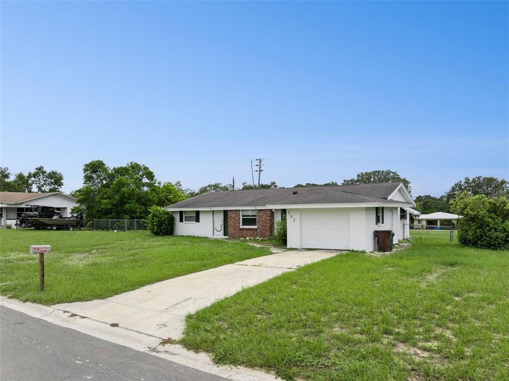 A single-story house with a white exterior, a brick accent wall, and a concrete driveway — 702 WILDABON AVENUE, LAKE WALES, FL