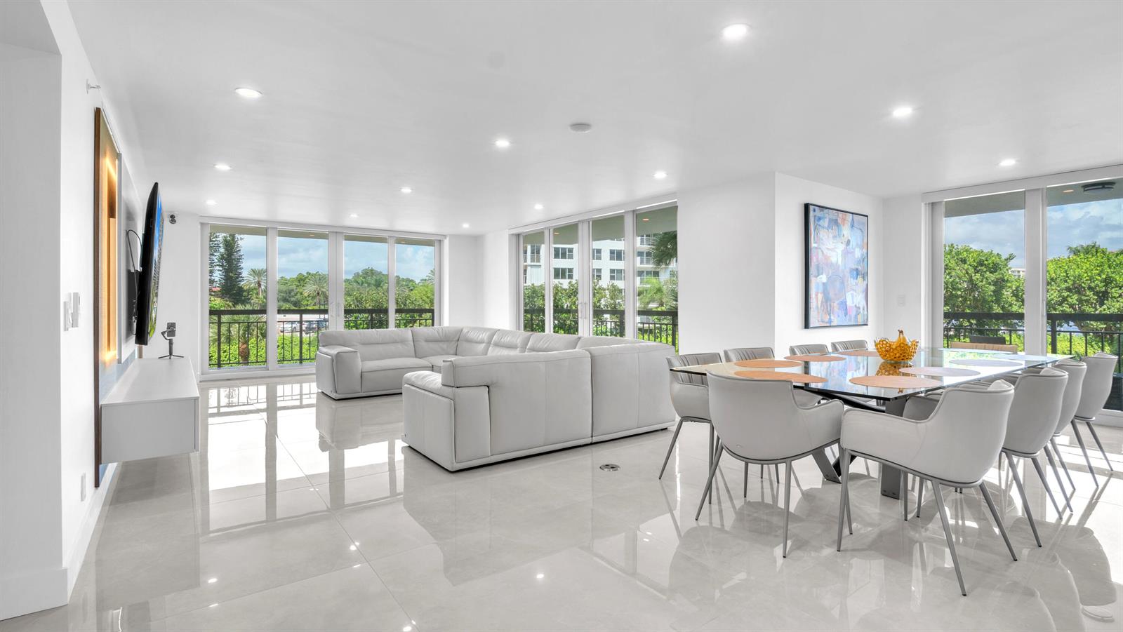 A bright, open-concept living and dining area features white leather furniture, tile floors, and balconies — 901 E Camino Real # 2a, Boca Raton FL 33432, BOCA RATON, FL