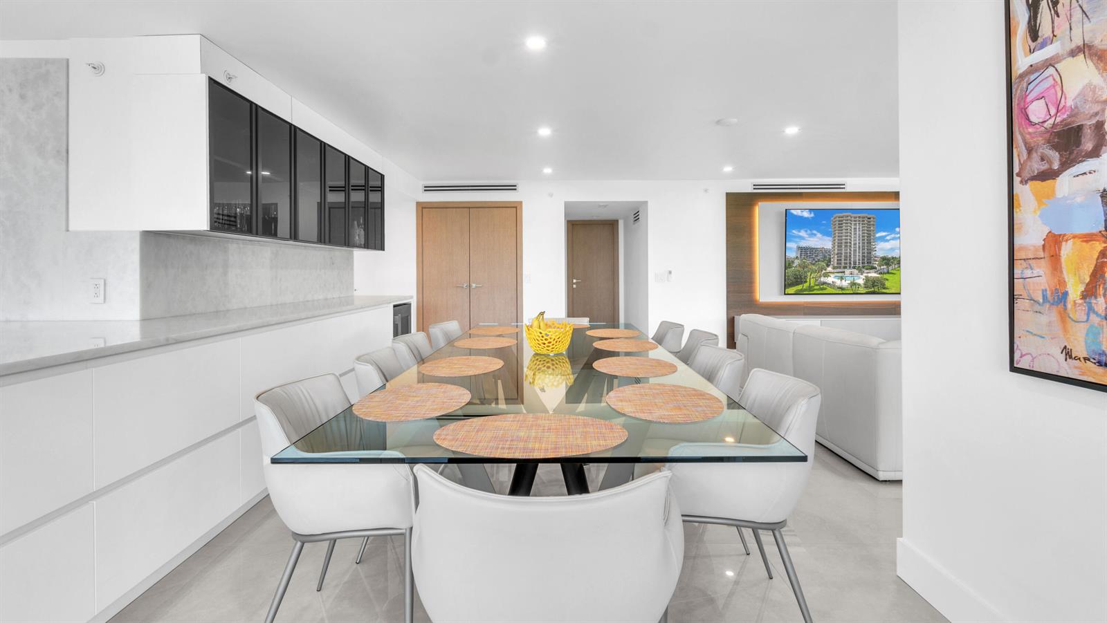 A modern dining room features a glass table with ten chairs and white cabinetry — 901 E Camino Real # 2a, Boca Raton FL 33432, BOCA RATON, FL