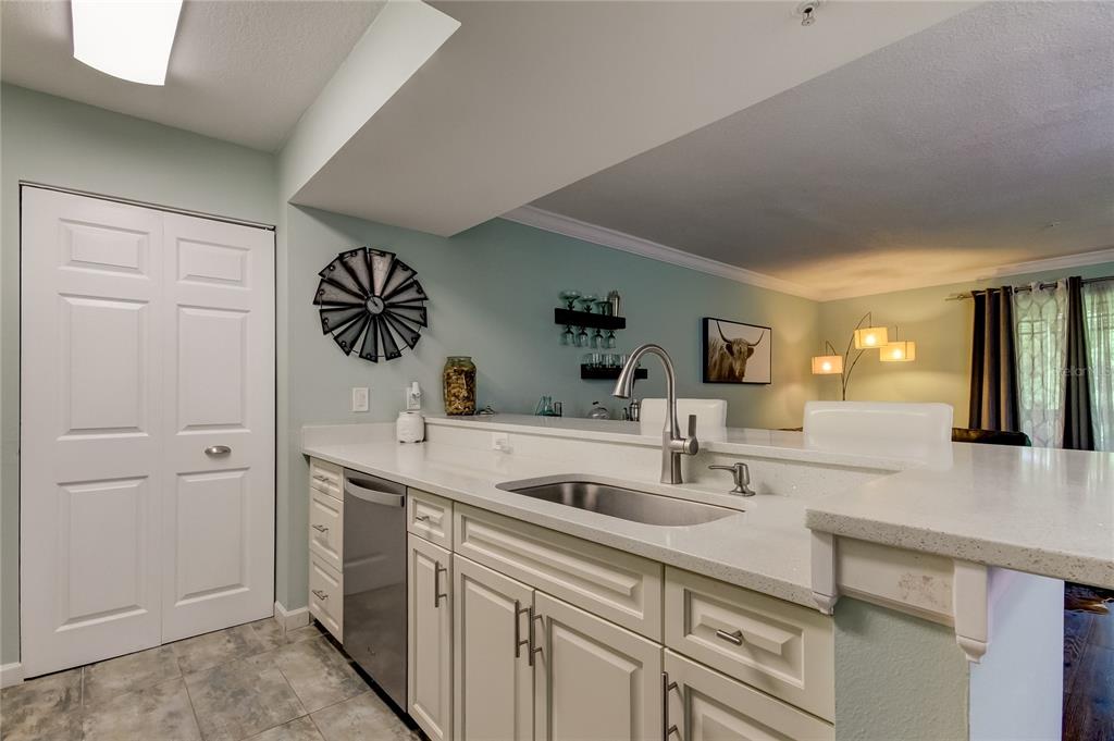 A kitchen features white cabinets, a stainless steel sink, and a breakfast bar — 2400 FEATHER SOUND DRIVE UNIT 1228, CLEARWATER, FL
