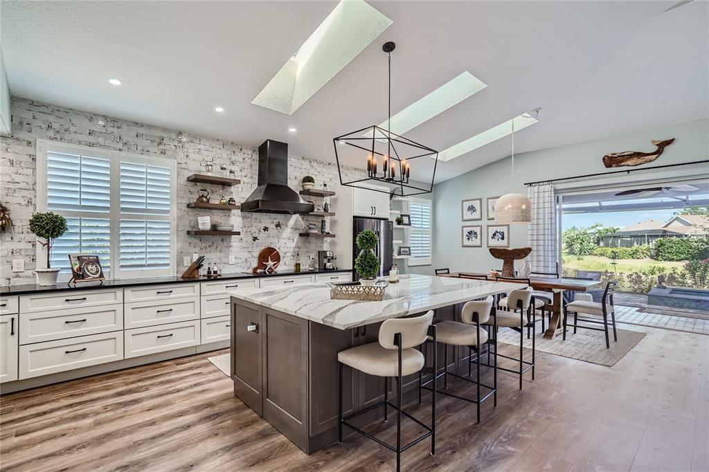 A kitchen features a large island, white cabinets, a brick wall, and two skylights — 11367 PERICO ISLE CIRCLE, BRADENTON, FL