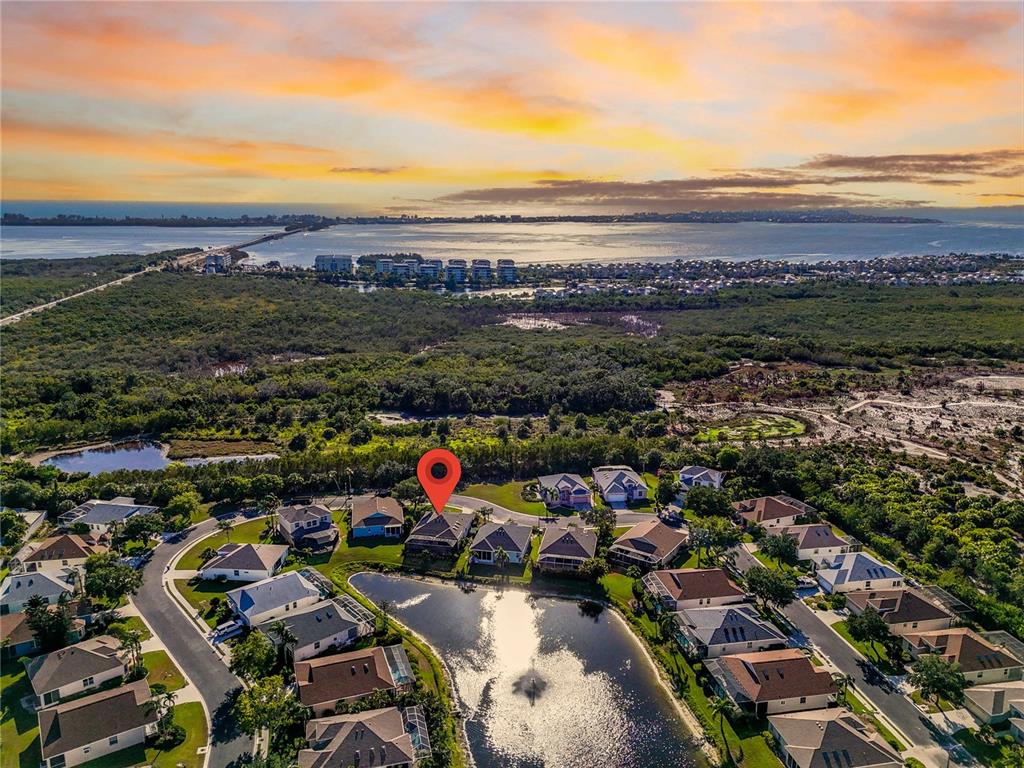 An aerial view shows a residential neighborhood with a pond and a distant coastline — 11367 PERICO ISLE CIRCLE, BRADENTON, FL