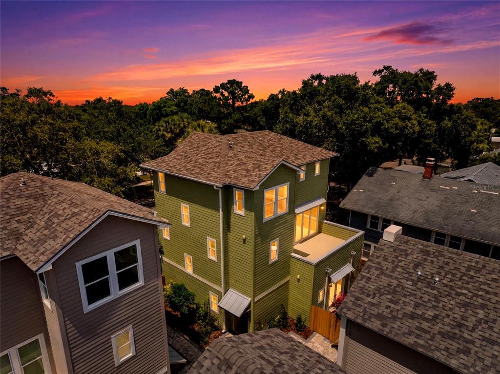 An aerial view shows a green multi-story house at sunset between two neighboring homes — 2540 1ST AVENUE N, ST PETERSBURG, FL