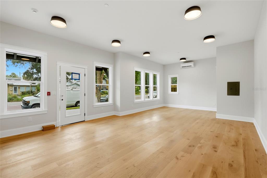 An empty room with light wood floors, white walls, multiple windows, and ceiling-mounted light fixtures — 2540 1ST AVENUE N, ST PETERSBURG, FL