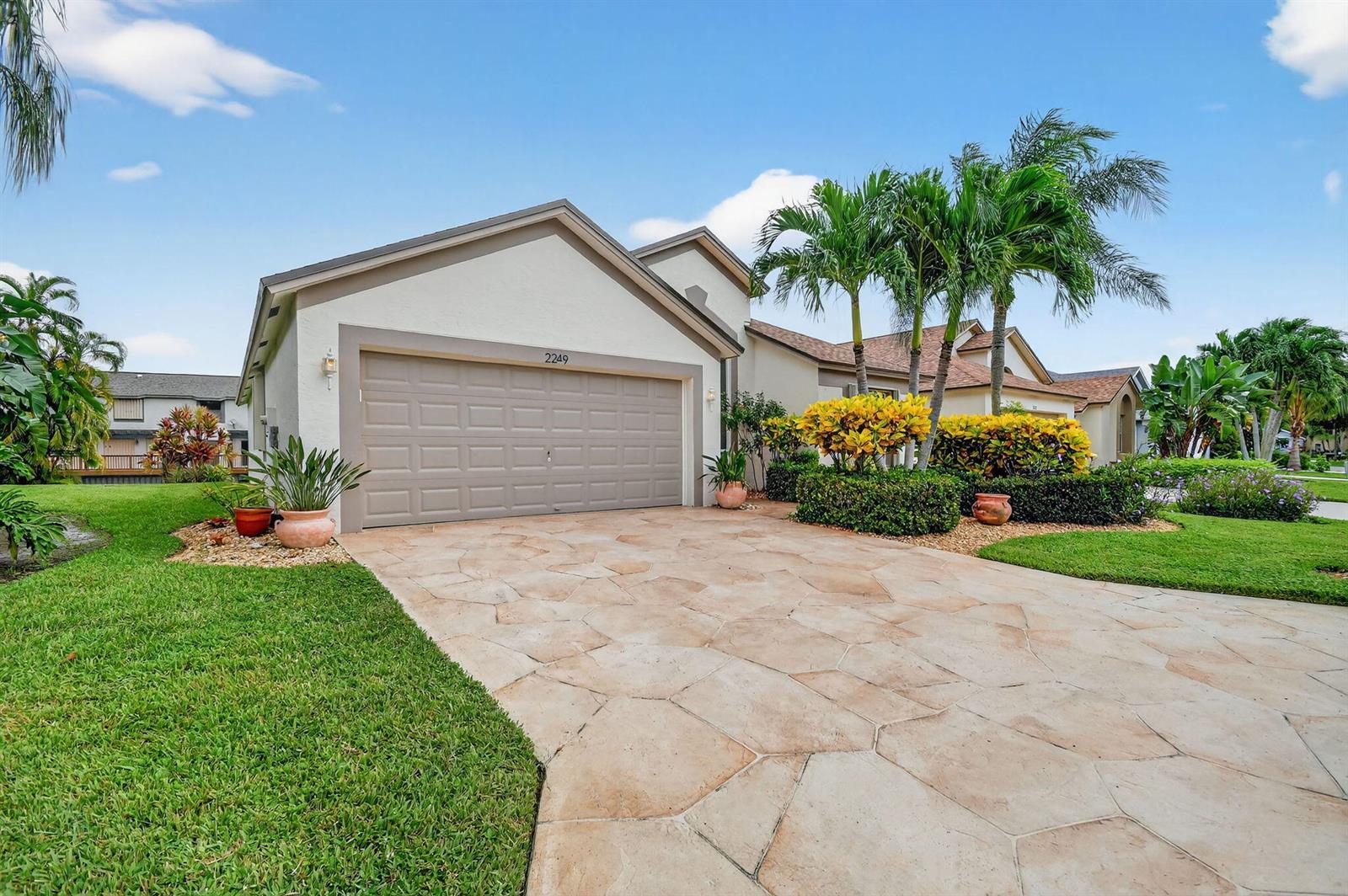 A single-story house with a stone-patterned driveway, a two-car garage, and palm trees — 2249 Soundings Court, FL 33413, FL