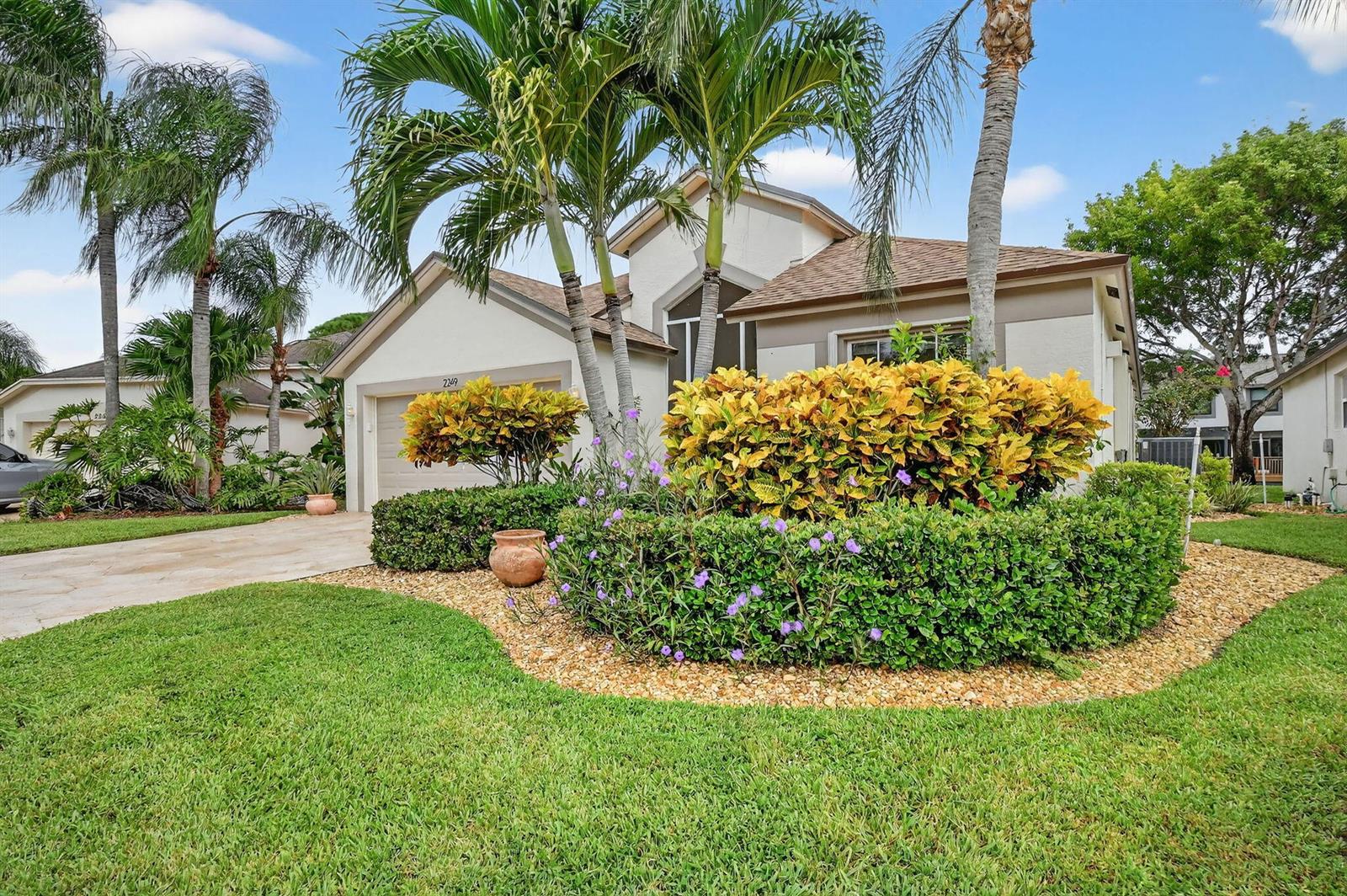 A single-story house with a beige exterior, palm trees, and a landscaped front garden — 2249 Soundings Court, FL 33413, FL