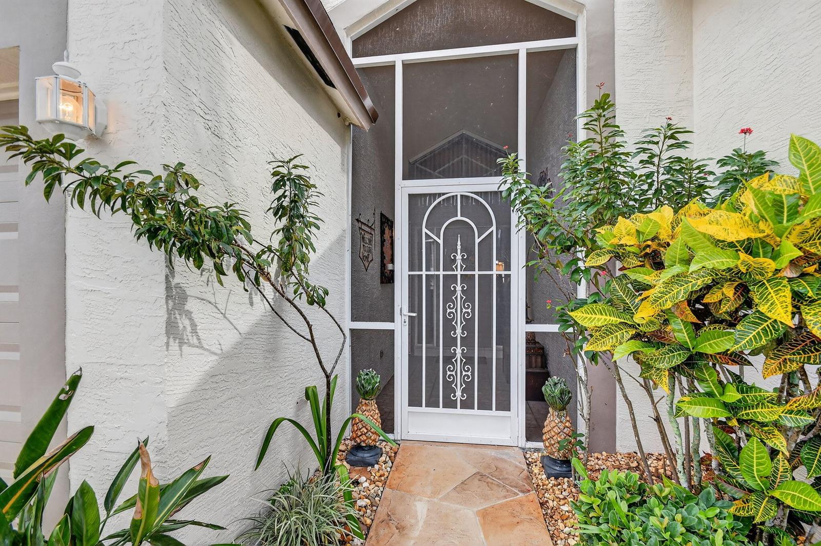 A white screen door with decorative metal scrollwork stands at the entrance of a home — 2249 Soundings Court, FL 33413, FL
