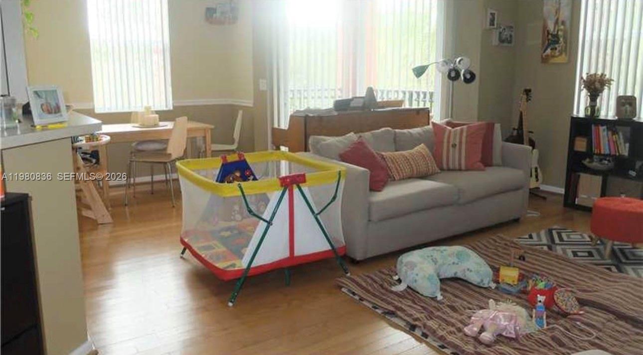 A living room with a gray sofa, a playpen, and a dining area in the background — 4600 SW 160th Ave # 620, Miramar FL 33027, MIRAMAR, FL