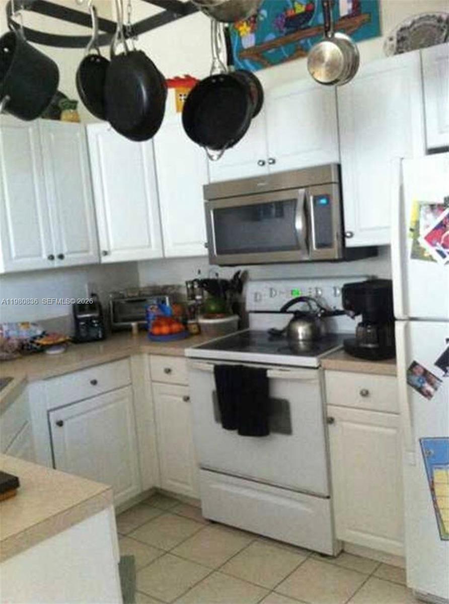 A kitchen features white cabinets, stainless steel appliances, and a hanging pot rack — 4600 SW 160th Ave # 620, Miramar FL 33027, MIRAMAR, FL