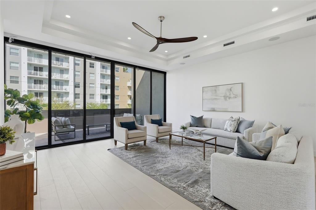A modern living room features light wood floors, a ceiling fan, and large sliding glass doors — 321 2ND STREET N, ST PETERSBURG, FL