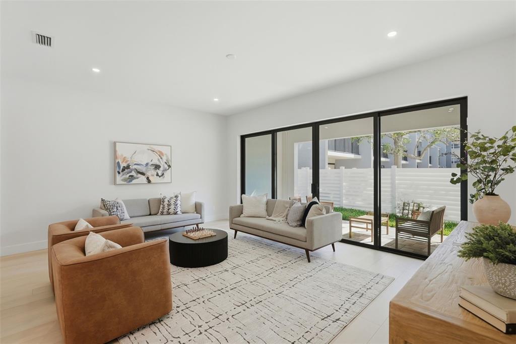 A modern living room features two sofas, leather armchairs, a round coffee table, and sliding doors — 321 2ND STREET N, ST PETERSBURG, FL