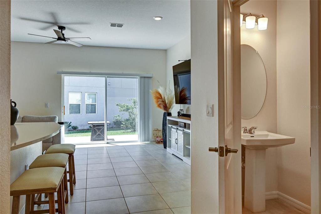 A view from a doorway into a living area with tile floors, sliding doors, and a bathroom — 1414 ANCHOR BEND WAY, KISSIMMEE, FL