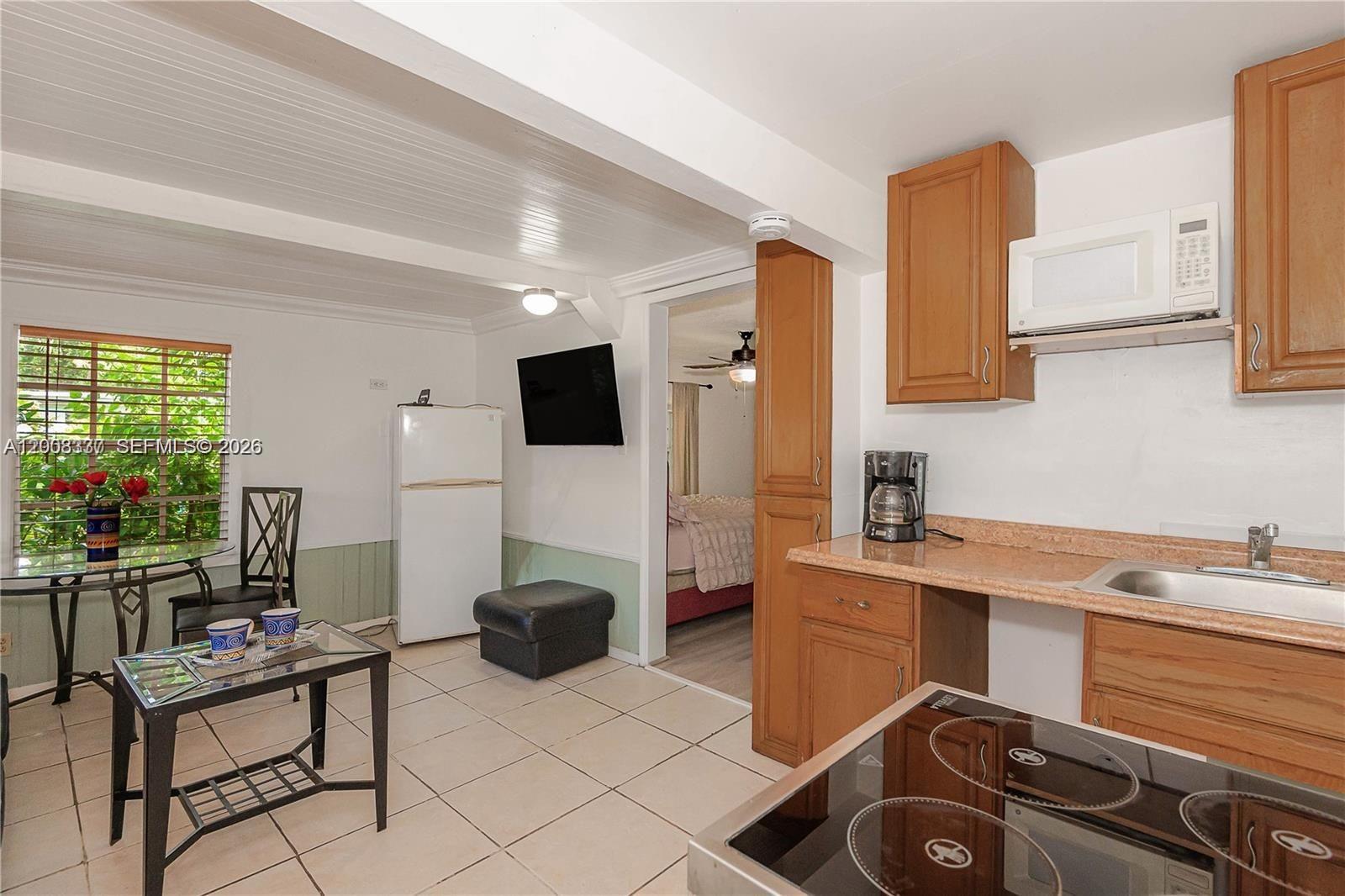 A small kitchen with wood cabinets, a glass-top stove, and an adjacent dining area — 1611 Fletcher St # 2, Hollywood FL 33020, HOLLYWOOD, FL