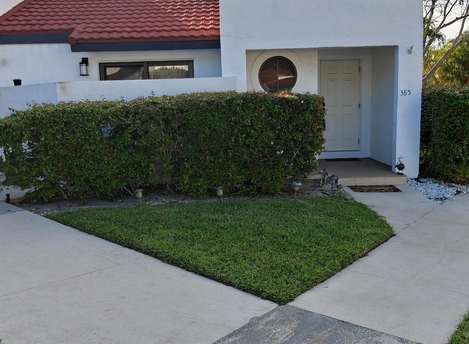 A white house exterior features a red tile roof, a hedge, and a small lawn — 385 NW 36th Avenue, Deerfield Beach FL 33442, DEERFIELD BEACH, FL