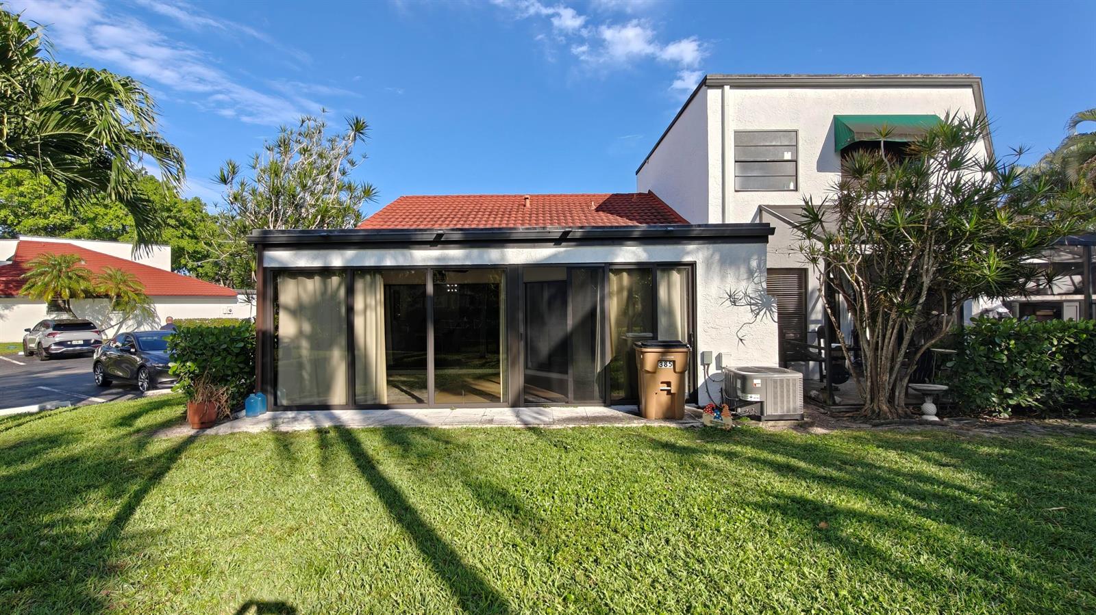 The exterior of a two-story home features a flat-roofed sunroom with large sliding glass doors — 385 NW 36th Avenue, Deerfield Beach FL 33442, DEERFIELD BEACH, FL