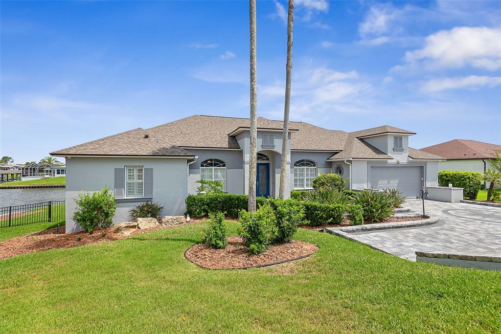A single-story house with a gray exterior, a paved driveway, and a waterfront backyard — 72 CLUB HOUSE DRIVE, PALM COAST, FL