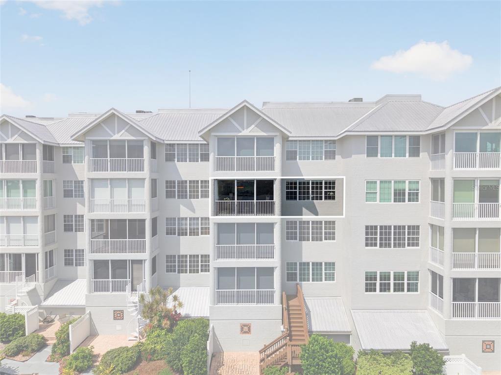 A white front door with a pineapple knocker sits on a tiled patio entrance — 1280 DOLPHIN BAY WAY UNIT 402, SARASOTA, FL