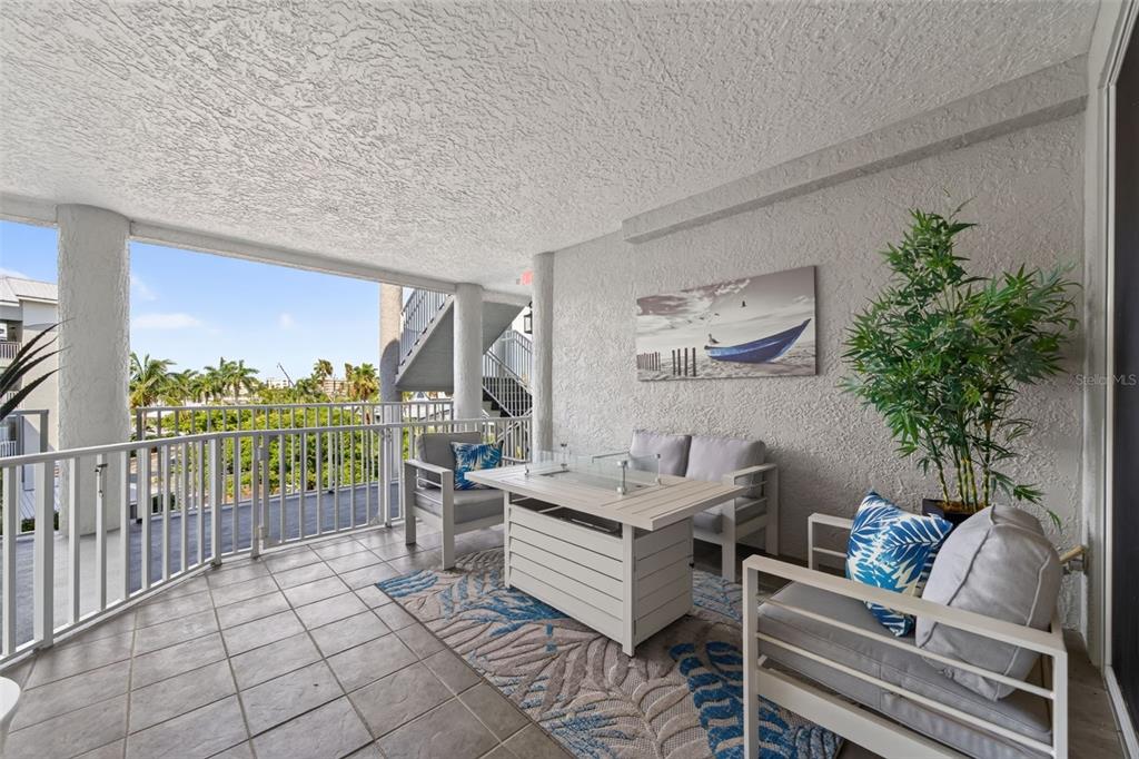 A covered balcony features white patio furniture, a fire pit table, and a front door — 1280 DOLPHIN BAY WAY UNIT 402, SARASOTA, FL