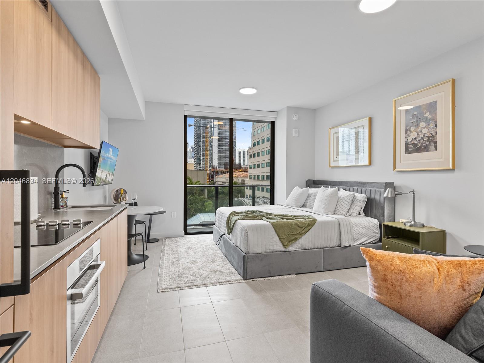 A studio apartment features a kitchenette, a bed, and a balcony with city views — 121 NE 5th St # 504, Miami FL 33132, MIAMI, FL