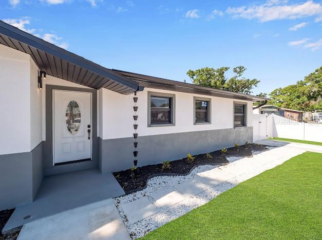 The exterior of a white and gray house features a front door and rain chain — 6040 84TH AVENUE N, PINELLAS PARK, FL