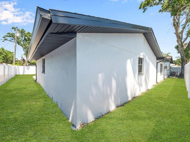 The exterior side of a white house with a dark roof stands on a lawn — 6040 84TH AVENUE N, PINELLAS PARK, FL