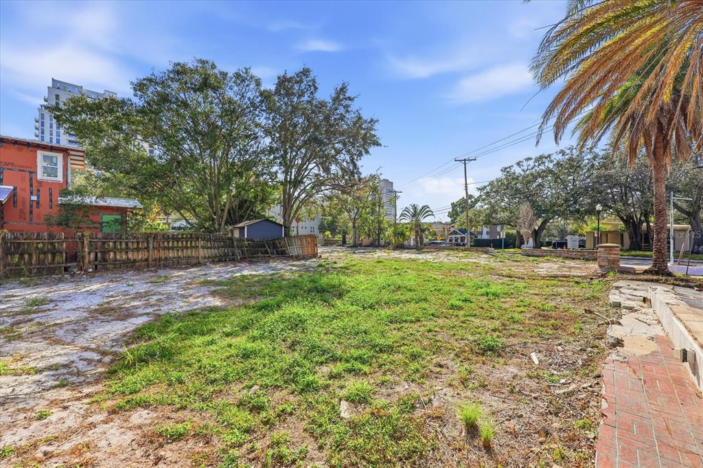 A vacant, grassy lot with a wooden fence and trees under a blue sky — 1504 S HOWARD AVENUE, TAMPA, FL