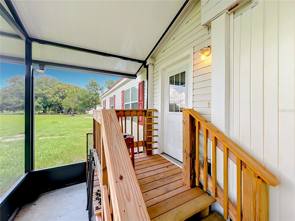 A wooden staircase leads to a white door on a covered, screened-in porch — 23834 COUNTY ROAD 33, GROVELAND, FL