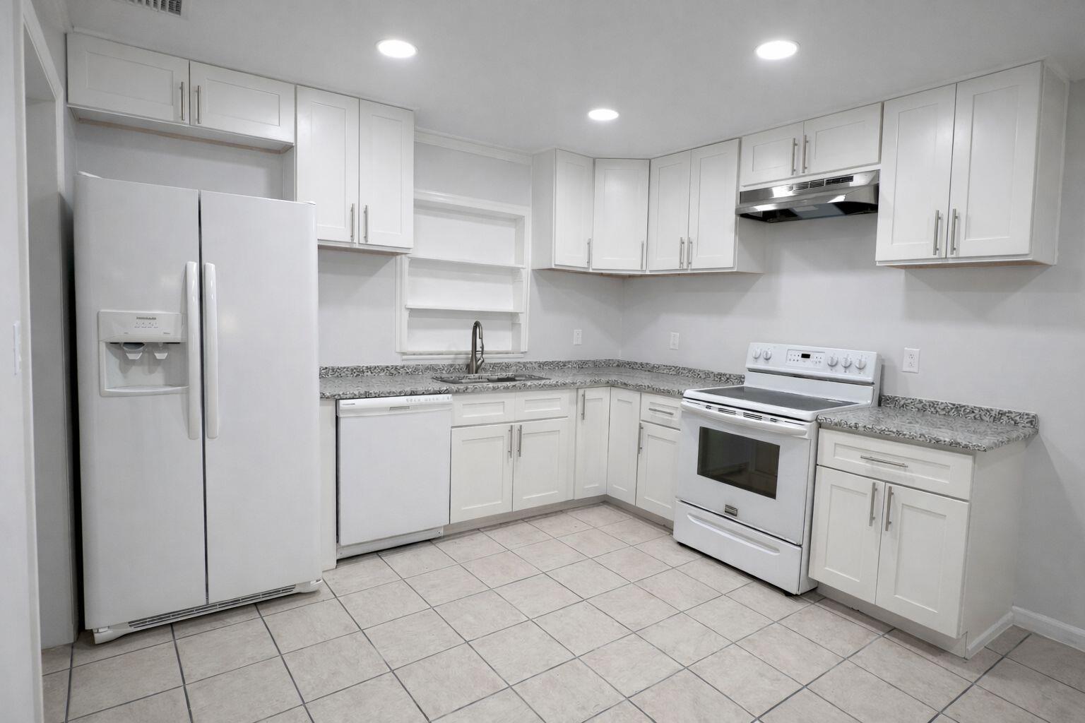 A kitchen with white cabinets, white appliances, granite countertops, and light-colored tile flooring — 1504 41st Avenue, Vero Beach FL 32960, VERO BEACH, FL