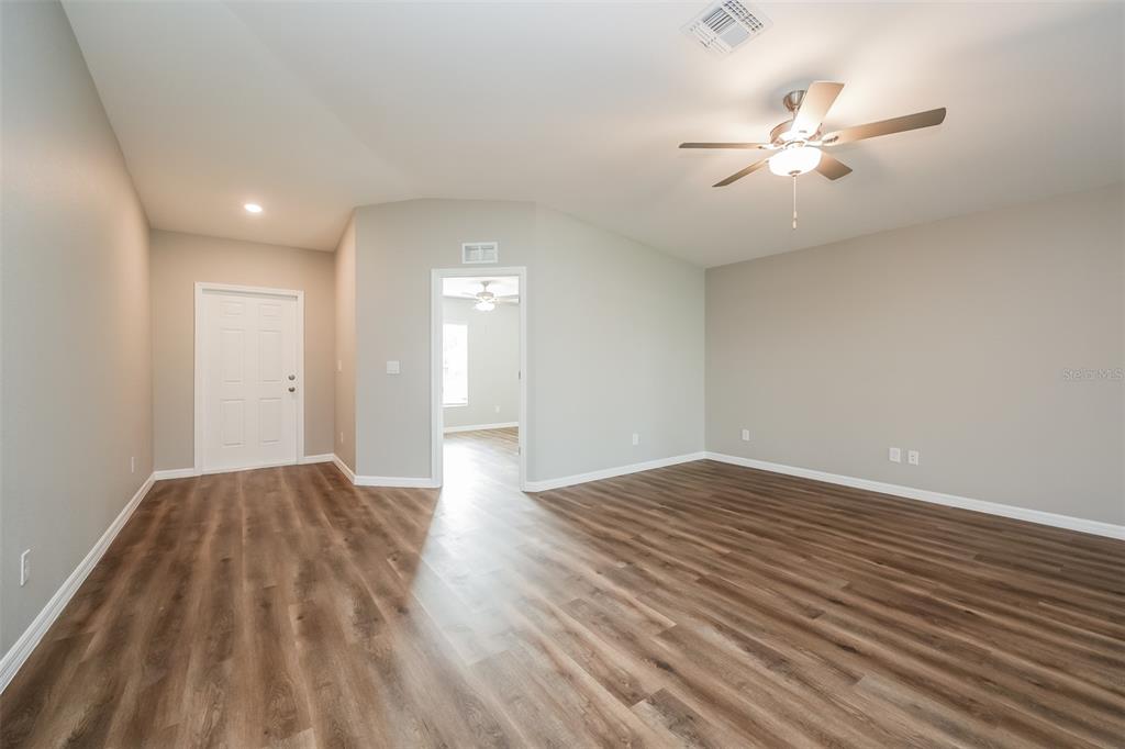 An empty room with light gray walls, wood-look flooring, a ceiling fan, and two doorways — 4458 WINDSONG AVENUE, NORTH PORT, FL