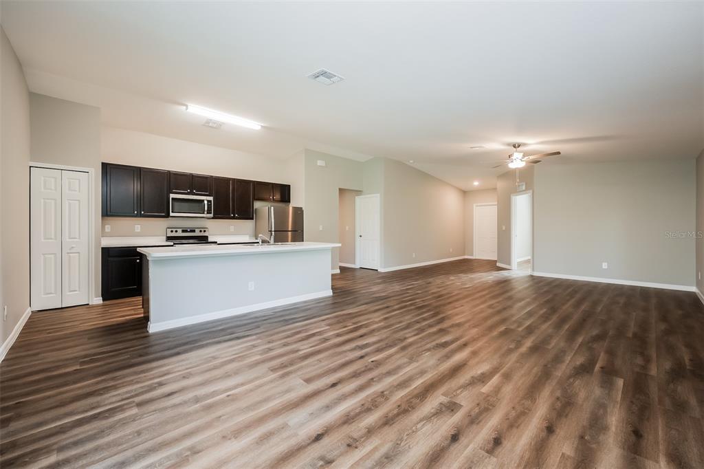 An open-concept kitchen with dark cabinets and a breakfast bar overlooks a spacious living area — 4458 WINDSONG AVENUE, NORTH PORT, FL