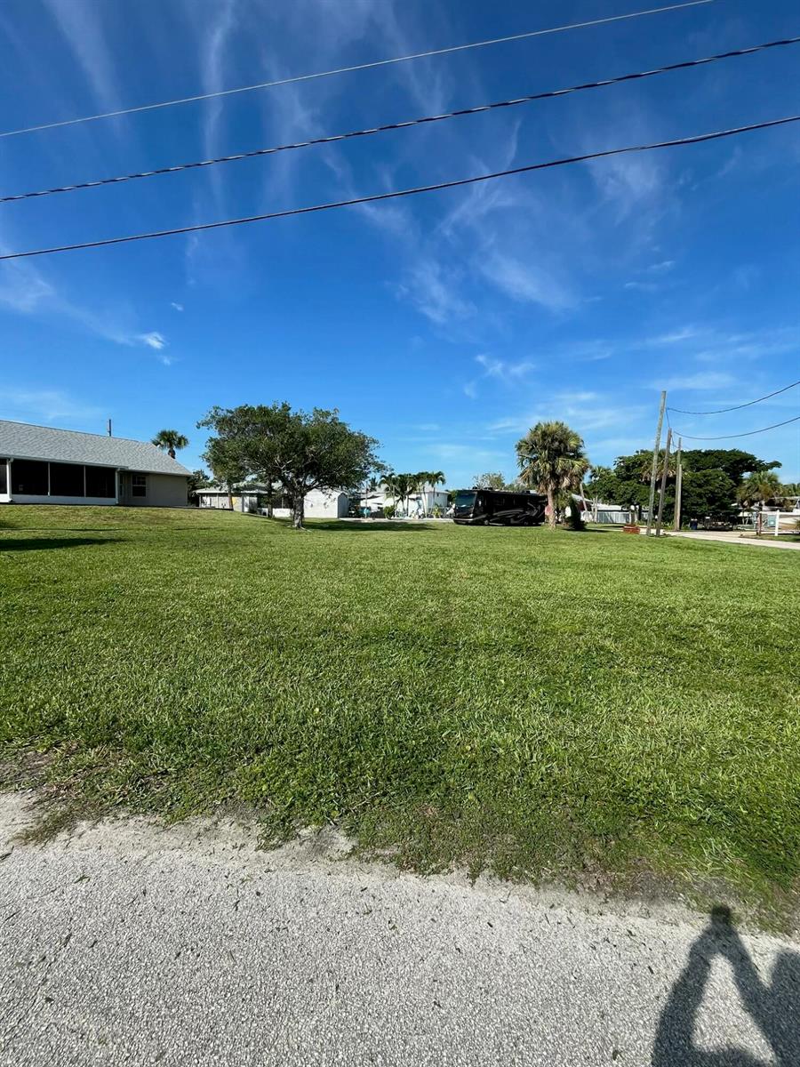 A grassy, vacant lot features a large tree and a parked motorhome under a blue sky — 0 Coral Circle, Fort Pierce FL 34949, FORT PIERCE, FL