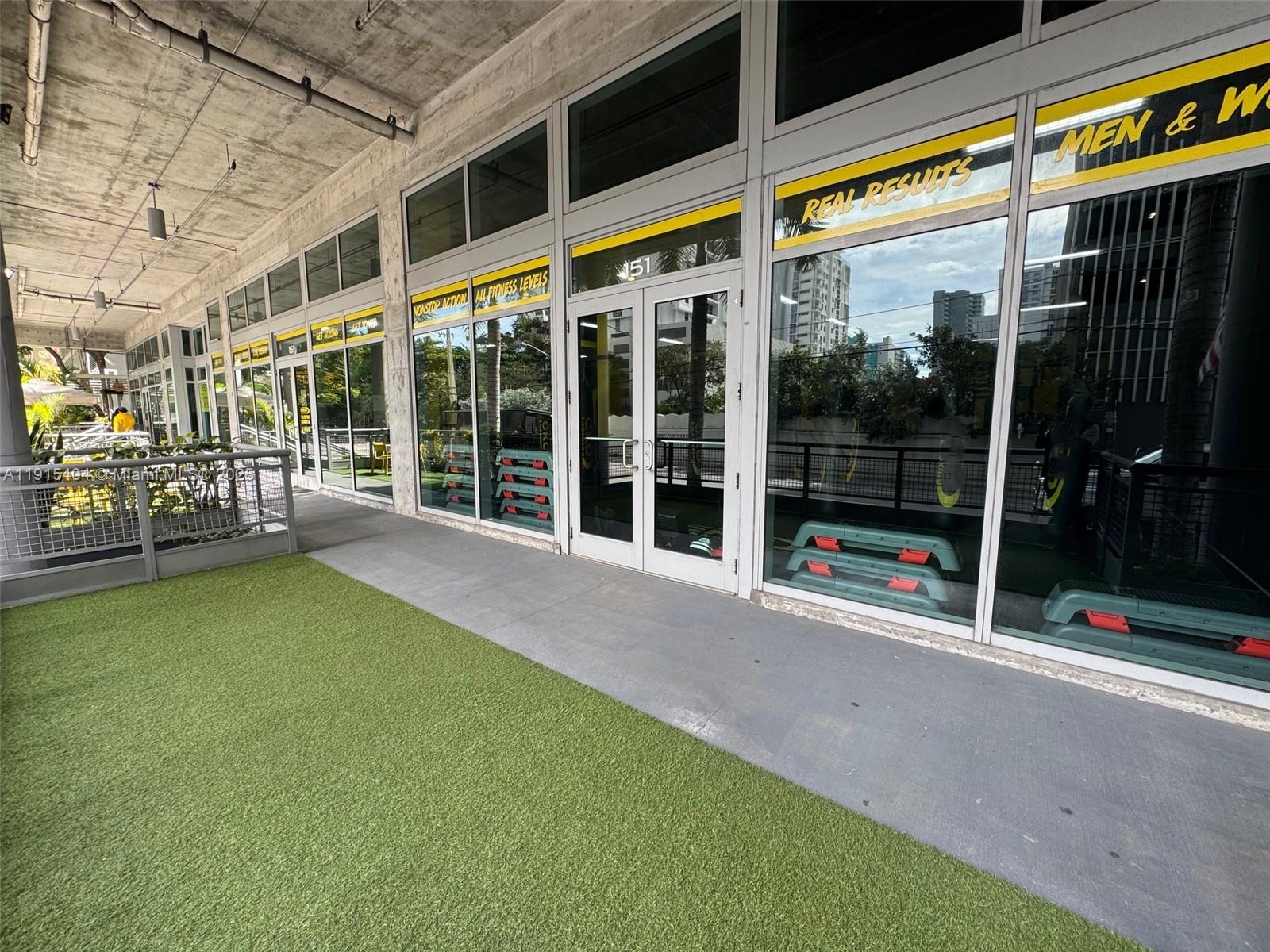 A gym exterior features glass doors, large windows, and a patch of artificial turf — 169 SW 7th St # D, Miami FL 33130, MIAMI, FL