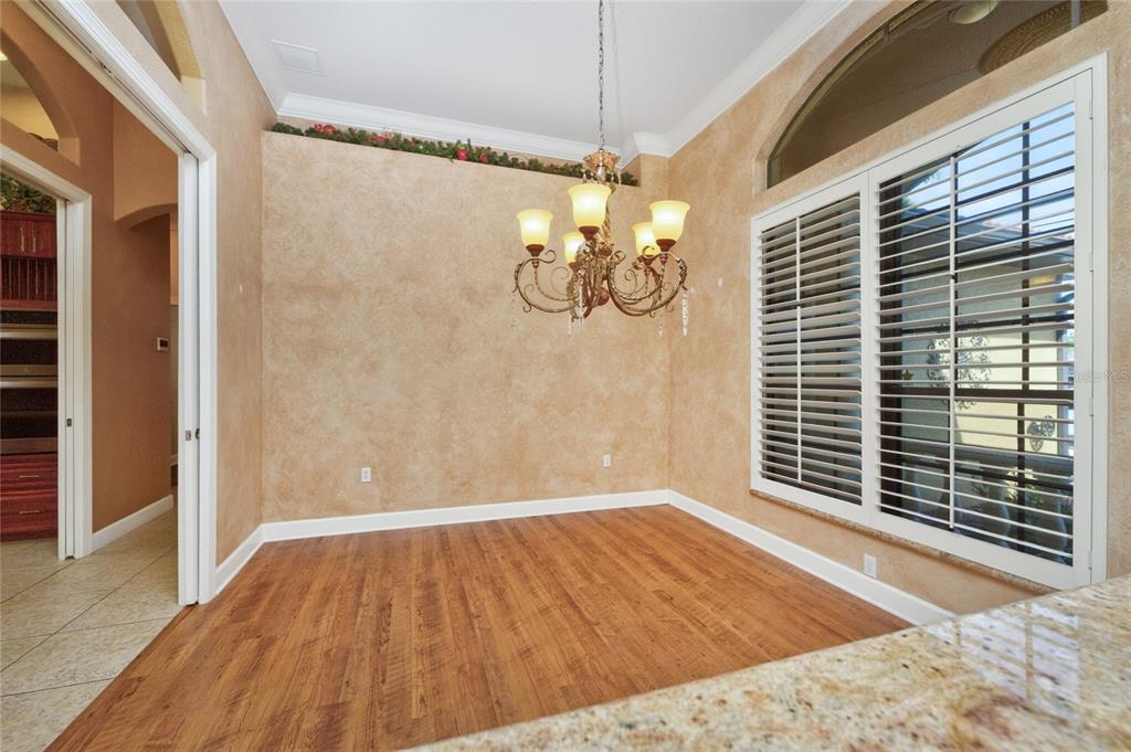 A dining room with wood-look flooring, a chandelier, and plantation shutters on a large window — 1141 ROTONDA CIRCLE, ROTONDA WEST, FL