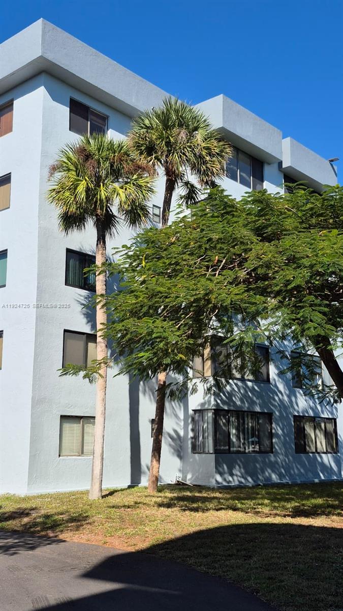 A low-angle view of a multi-story light blue apartment building with palm trees — 8020 Hampton Blvd # 202, North Lauderdale FL 33068, NORTH LAUDERDALE, FL