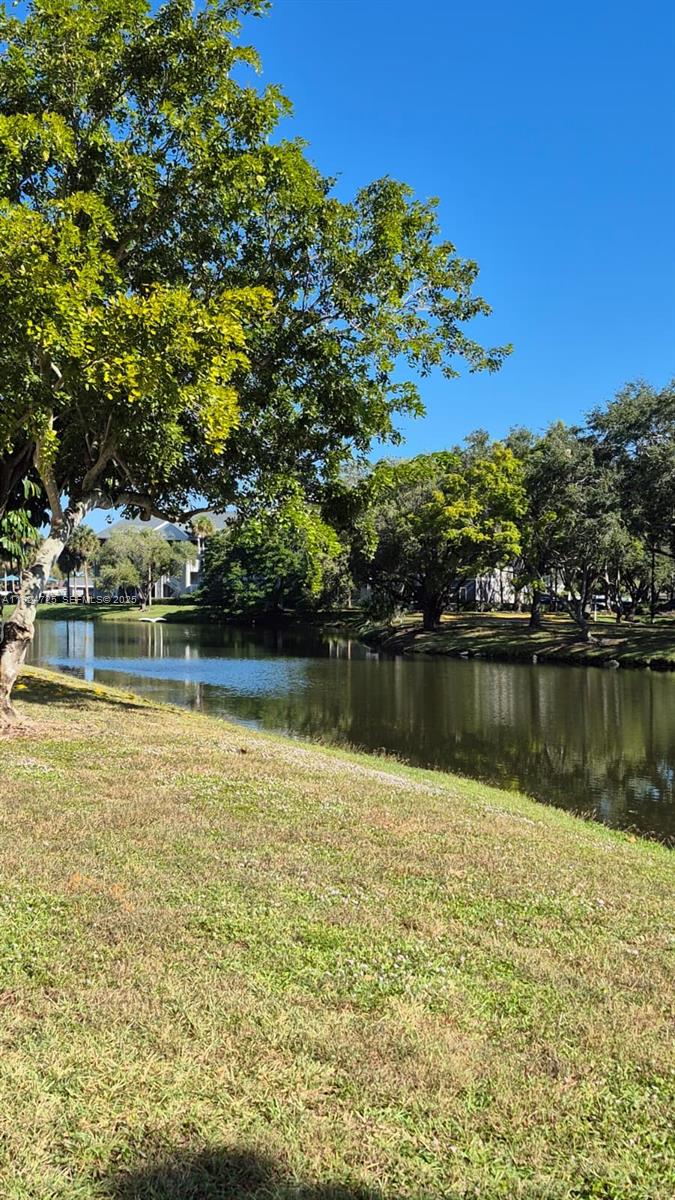 A grassy lawn slopes down toward a calm pond surrounded by mature green trees — 8020 Hampton Blvd # 202, North Lauderdale FL 33068, NORTH LAUDERDALE, FL